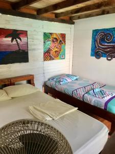 2 camas en una habitación con pinturas en la pared en Alojamiento playa blanca Barú. InHousecaribe, en Playa Blanca
