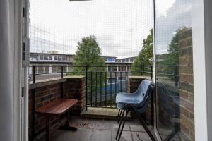 einen Balkon mit einem blauen Stuhl und einem Holztisch in der Unterkunft Stunning apartment in Dulwich in London