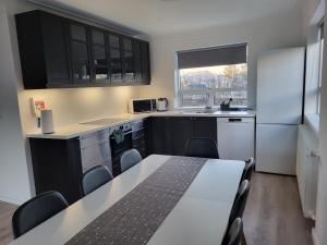 uma cozinha com armários pretos e um frigorífico branco em Guesthouse Maximilian em Keflavík
