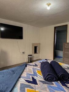 1 dormitorio con 1 cama y TV en la pared en Casa Espaciosa en Quetzaltenango