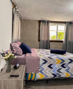 1 dormitorio con 1 cama y un jarrón de flores sobre una mesa en Casa Espaciosa en Quetzaltenango
