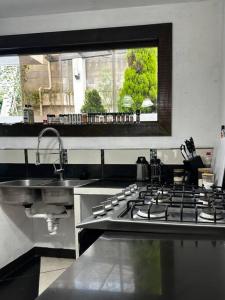 cocina con fogones, fregadero y ventana en Casa Espaciosa en Quetzaltenango