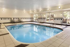 een groot binnenzwembad in een hotelkamer met tafels en stoelen bij Fairfield Inn & Suites by Marriott Toledo Maumee in Maumee