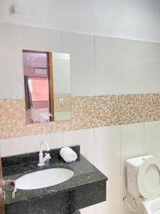 uma casa de banho com um lavatório, um WC e um espelho. em Pousada Villa Sambaqui em Penha