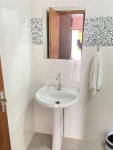 a white bathroom with a sink and a mirror at Pousada Villa Sambaqui in Penha