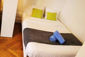 a white bed with green pillows and a blue towel at Le lumineux - Appartement central sur parquet chevrons - Chez Lulu in Nantes
