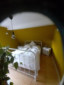 1 dormitorio con cama blanca y pared amarilla en Individuelle stilvolle Maisonettewohnung mit zwei Schlafzimmern, zwei Bädern und Sauna am Rothaarsteig en Hilchenbach
