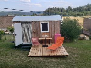 een houten terras met stoelen en een tafel en een schuur bij Individuelle stilvolle Maisonettewohnung mit zwei Schlafzimmern, zwei Bädern und Sauna am Rothaarsteig in Hilchenbach
