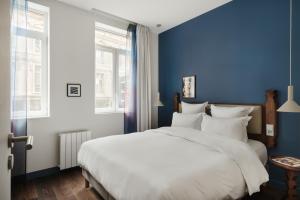 - une chambre avec un grand lit blanc aux murs bleus dans l'établissement Edgar Suites Lille - Faidherbe, à Lille