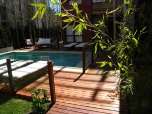 una terraza de madera con mesa de cristal y piscina en Posta Cangrejo Apart en Las Gaviotas