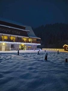 a building with lights in the snow at night at Lawendowy Staw in Cisna