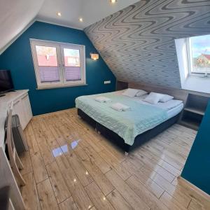 a bedroom with a bed with blue walls and a wooden floor at Helios in Ustka