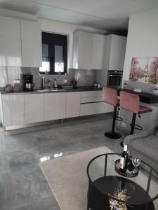 Una cocina con gabinetes blancos y una mesa y un sofá. en Olina's Luxury Apartment, en Tríkala