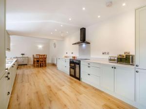 a kitchen with white cabinets and a wooden floor at 3 bed in Bedale 88242 in Well