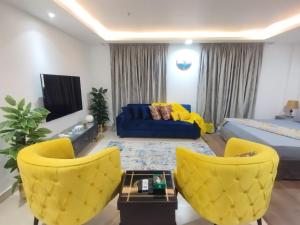 uma sala de estar com cadeiras amarelas e um sofá azul em Luxury one bed Apartment in Gold Crest Mall And Residency DHA Lahore em Lahore