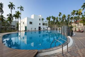 a swimming pool in front of a building with palm trees at Malnad Shire Eco Resort in Shimoga