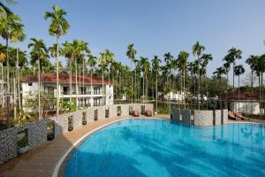 einen Pool in einem Resort mit Palmen in der Unterkunft Malnad Shire Eco Resort in Shimoga
