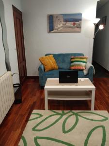 ein Wohnzimmer mit einem blauen Sofa und einem Tisch in der Unterkunft Apartamento Etxe Morea, Casco Histórico in Bermeo