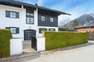 a white house with black windows and a fence at Berghupferl in Garmisch-Partenkirchen