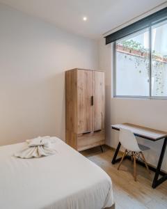 1 dormitorio con cama, escritorio y ventana en Anima 64, en Bogotá
