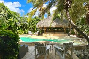 uma piscina com duas cadeiras e uma cabana em Ocean View Villas em Kralendijk