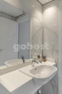 Baño blanco con lavabo y espejo en Elegant Villa Morra Apartment Bbqbalconygympool, en Asunción