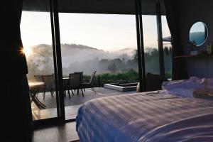 a bedroom with a bed and a balcony with a table at WC Coffee&ไร่หวานซึ้ง in Mae Hong Son