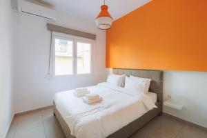 sypialnia z dużym białym łóżkiem z pomarańczową ścianą w obiekcie Colourful cosy apartment at Panormou metro station w Atenach