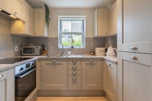 a kitchen with white cabinets and a sink and a window at Badgers Lodge MV37 Lakeside Spa Property in Somerford Keynes
