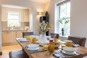 a dining room table with a vase of flowers at Badgers Lodge MV37 Lakeside Spa Property in Somerford Keynes