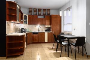 ヴロツワフにあるZabrodzka Family Apartmentのキッチン(木製キャビネット、テーブル、椅子付)