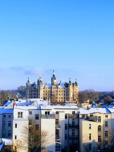 a large building with snow on the roofs of buildings at Schlossblick - Modernes & zentrales Apartment mit Balkon und Arbeitsplatz in Schwerin