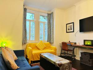 sala de estar con sofá amarillo y mesa en London SW Holiday Apartment - Free parking, en Londres