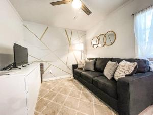 ein Wohnzimmer mit einem schwarzen Sofa und einem TV in der Unterkunft Cozy cottage in the heart of COS - pet friendly in Colorado Springs