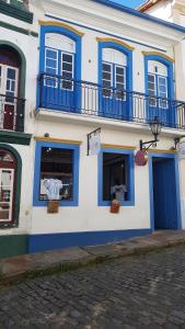 a white and blue building with blue windows and a street at Suite Tomaz Gonzaga in Ouro Preto