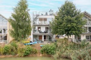 an apartment building with a river in front of it at Calm Waters HM95 HOT TUB Lakeside Spa Property in Somerford Keynes