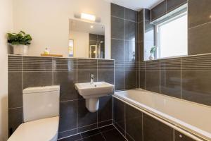 a bathroom with a toilet and a sink and a bath tub at Calm Waters HM95 HOT TUB Lakeside Spa Property in Somerford Keynes