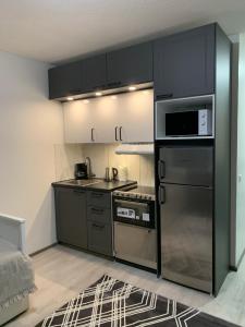a small kitchen with black cabinets and a microwave at Yksiö keskustassa saunalla in Iisalmi