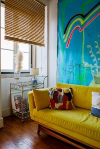 um sofá amarelo numa sala de estar com um quadro em Palm Tree House, Central apartemant in Principe Real em Lisboa