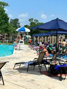 un grupo de personas sentadas en sillas de césped junto a una piscina en Cozy on the golf course!, en Humble