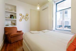 um quarto com uma cama, uma cadeira e uma janela em Palm Tree House, Central apartemant in Principe Real em Lisboa