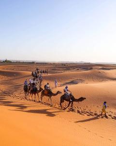 a group of people riding horses in the desert at Nomads Luxury Camp Merzouga in Adrouine