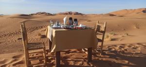 a table and chairs in the sand in the desert at Nomads Luxury Camp Merzouga in Hassilabied