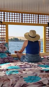 a woman in a hat sitting on a bed at Aswan Nile Felucca hotel in Aswan