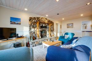 a living room with a stone fireplace and blue chairs at Dreamy Port Orford Home with Oceanfront Views in Port Orford