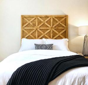 um quarto com uma cama branca e uma cabeceira em madeira em Saxon Inn em Alfred