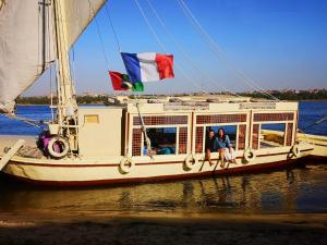 two people sitting on a boat with flags on it at Aswan Felucca sailing boat and Hotel in Aswan +121 photos
