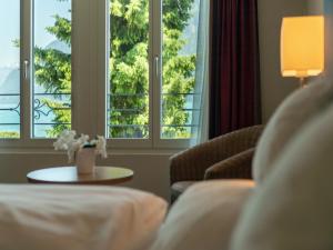 una sala de estar con 2 ventanas y una mesa con flores en Hotel Seeburg - Adults only en Ringgenberg