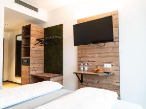 a bedroom with two beds and a flat screen tv on a wall at SEKRA Stadthotel 