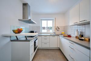 une cuisine blanche avec des placards blancs et une fenêtre dans l'établissement apanoxa homes I zentral I Parkplätze I Deluxe Apartment, à Straubing